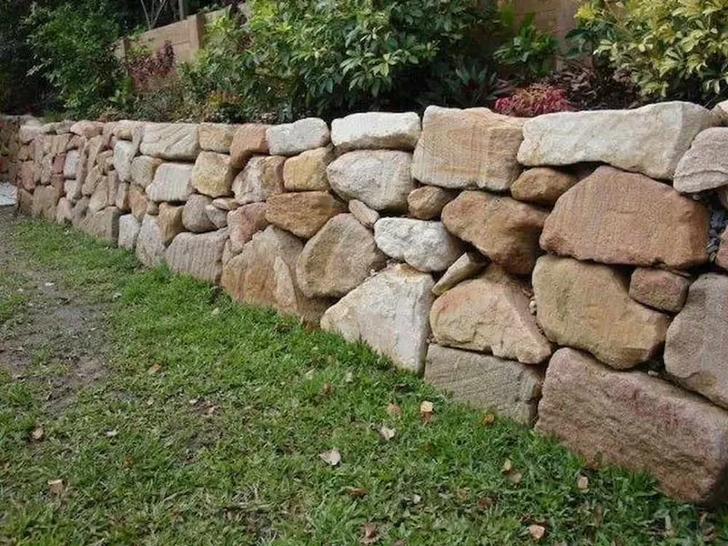 Natural boulder retaining wall construction for hillside stability and erosion control featuring boulder placement sequencing for slope retention and natural aesthetics in Post Falls, Coeur d'Alene, and North Idaho, gallery view 2