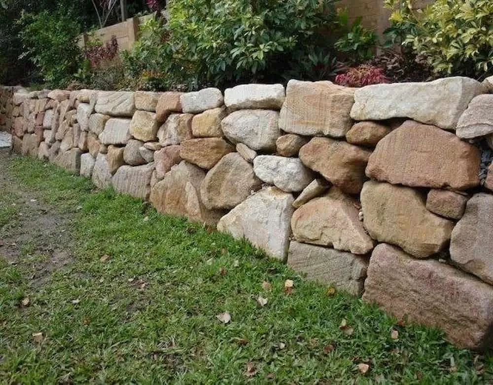 Natural boulder retaining wall construction for hillside stability and erosion control featuring boulder placement sequencing for slope retention and natural aesthetics in Post Falls, Coeur d'Alene, and North Idaho, gallery view 1