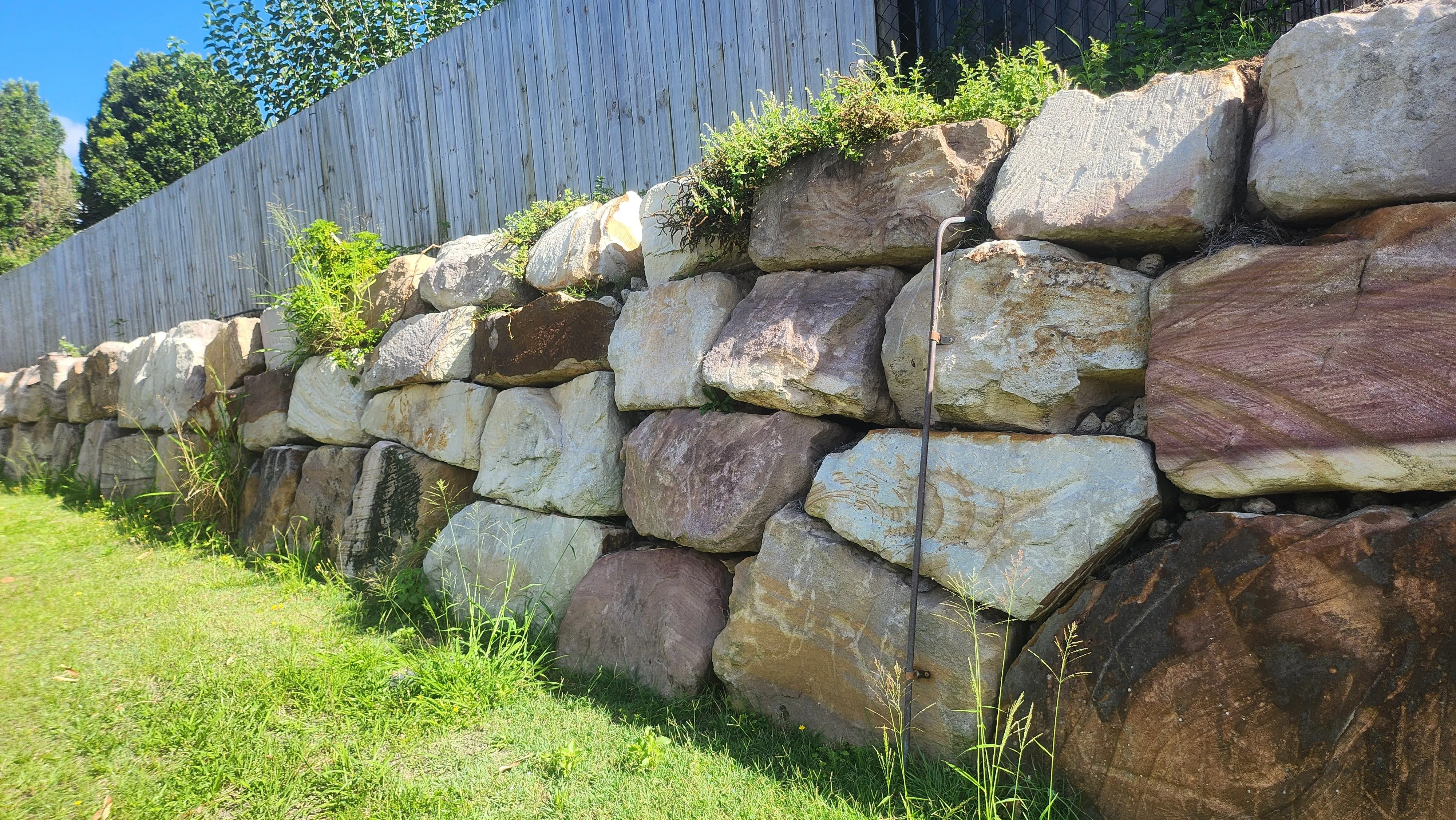 Natural boulder retaining wall construction for hillside stability and erosion control featuring boulder placement sequencing for slope retention and natural aesthetics in Post Falls, Coeur d'Alene, and North Idaho